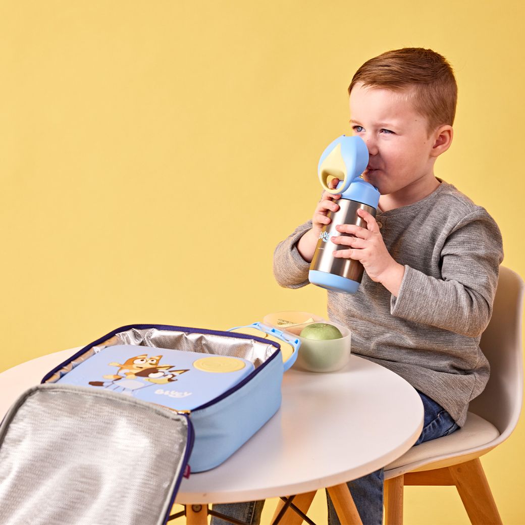 child sitting at a table drinking a b.box bluey drink bottle